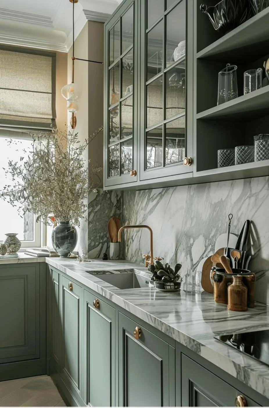 Sage green cabinets with a marble backsplash and glass uppers